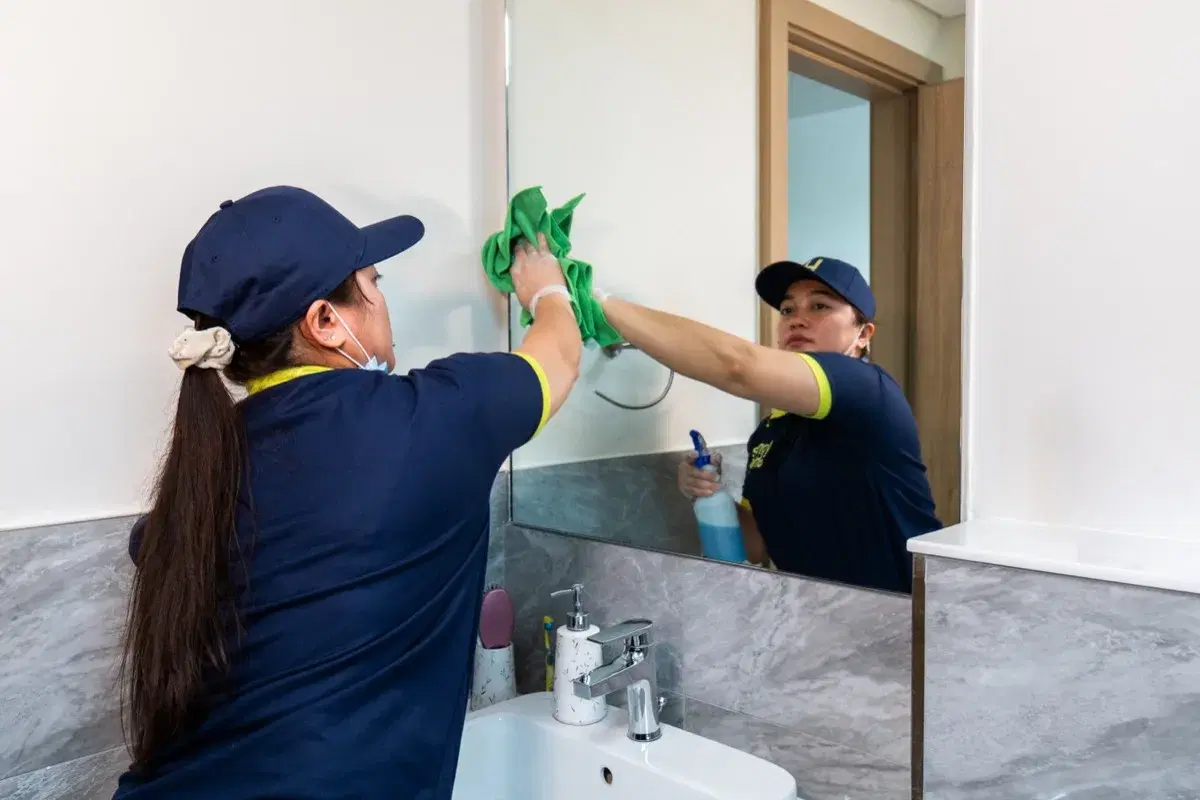 Polishing the bathroom mirror during a deep clean