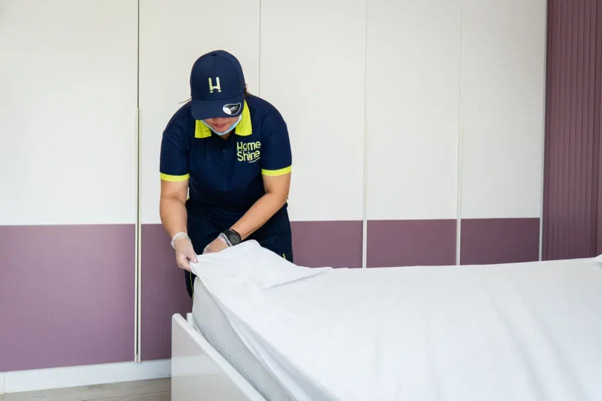 Fitting a fresh sheet on the bed during a turnover